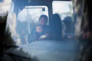 Un hombre alimenta a un niño a su llegada, en bus, a un centro de recepción para desplazados en Zaporiyia, Ucrania, el 2 de mayo de 2022. (AP Foto/Francisco Seco)