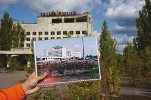 Ayer y hoy, un guía sostiene en su mano la imagen de unos edificios en el mismo lugar en el que hoy permanecen abandonados