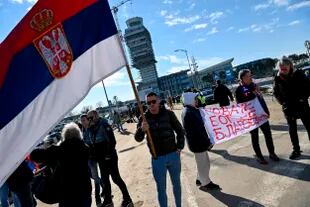 La gente sostiene una pancarta que dice "Novak, Dios te bendiga", en el aeropuerto de Belgrado