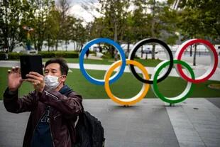 Un hombre toma fotografías frente a los Anillos Olímpicos fuera del Museo Olímpico de Japón en Tokio