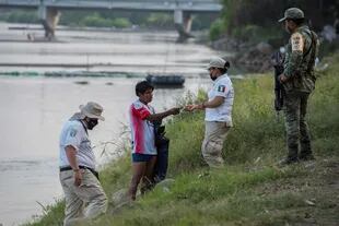 Funcionarios del Instituto Nacional de Migración de México (INM) verifican documentación de personas que cruzaron el río Suchiate de Guatemala a México el 17 de enero de 2021 mientras se espera que una nueva caravana migrante llegue a la frontera mexicana con Guatemala