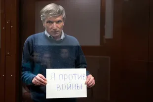 Alexei Gorinov sostiene un cartel que dice "Estoy en contra de la guerra" mientras está de pie en una jaula durante una audiencia en la sala del tribunal en Moscú, Rusia