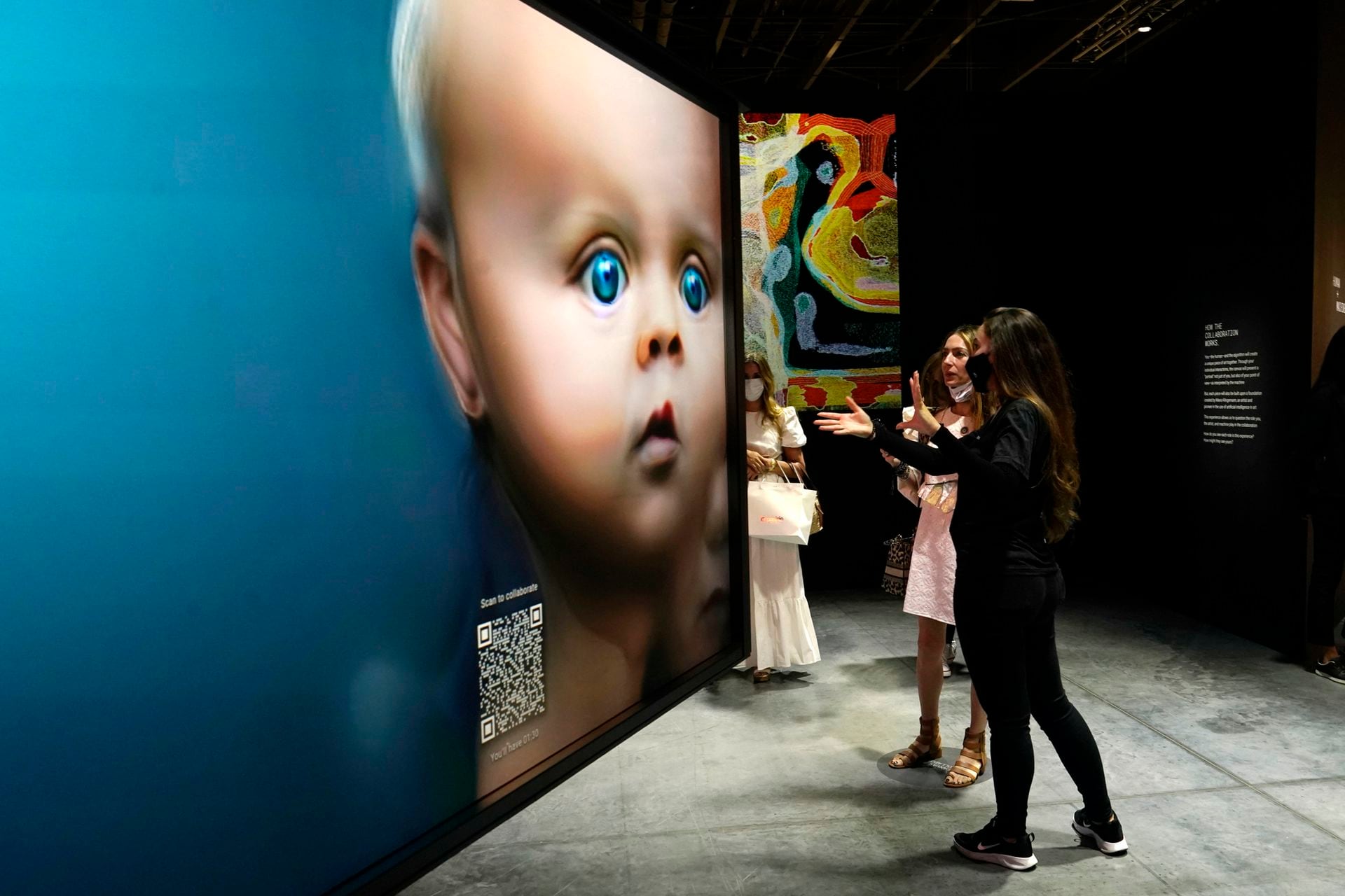La gente mira las obras de arte de NFT en la exposición de Tezos durante el Art Basel Miami Beach