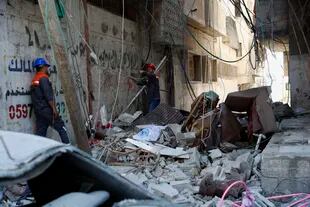 Los trabajadores inspeccionan los escombros del edificio destruido de Abu Hussein que fue alcanzado por un ataque aéreo israelí 
