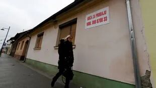 Una transeúnte pasa frente a una casa vacía con un anuncio de venta en el este de Croacia, en diciembre de 2021