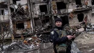 Un oficial de policía ucraniano se encuentra frente a un bloque residencial dañado por un ataque con misiles
