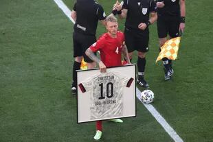 El defensor danés Simon Kjaer sostiene una camiseta enmarcada del mediocampista danés Christian Eriksen antes del inicio del partido de fútbol del Grupo B de la UEFA EURO 2020 entre Dinamarca y Bélgica en el Estadio Parken de Copenhague el 17 de junio de 2021 (Foto de HANNAH MCKAY / POOL / AFP). )
