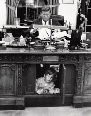 Una famosa imagen tomada en 1962, donde John John se esconde debajo del escritorio de su padre, el presidente demócrata, John F. Kennedy.