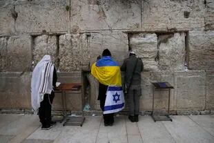 Un judío ultraortodoxo envuelto en banderas nacionales de Ucrania e Israel reza en el Muro Occidental, el lugar más sagrado donde los judíos pueden rezar en la Ciudad Vieja de Jerusalén, el viernes 4 de marzo de 2022