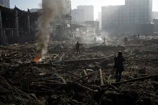 People gather amid the destruction caused after shelling of a shopping center, in Kyiv, Ukraine, Monday, March 21, 2022. (AP Photo/ (AP Photo/Rodrigo Abd)