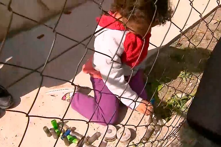Arrodillada, una nena juega con los cartuchos de las balas de gomas y los casquillos de gas lacrimógeno empleados en el desalojo de los terrenos usurpados