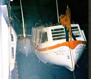 En la foto, uno de los tripulantes filipinos que había permanecido a bordo tratando de bajar un bote salvavidas colgado en el costado de babor del barco