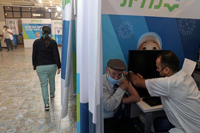 Un trabajador de la salud aplica una tercera dosis de la vacuna de Pfizer/BioNTech a un adulto mayor en Israel