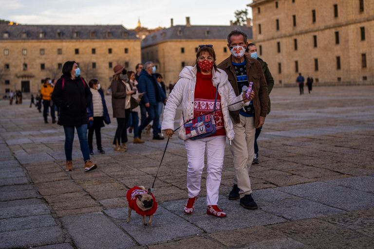 Personas con mascarillas para frenar los contagios de COVID-19 caminan por San Lorenzo de El Escorial, España, el domingo 2 de enero de 2022. (AP Foto/Manu Fernández)