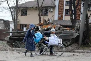 Civiles pasan por delante de un taque destrozado durante los intensos combates en una zona controlada por fuerzas separatistas prorrusas en Mariúpol, Ucrania, el 19 de abril de 2022. (AP Foto/Alexei Alexandrov)