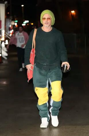 Brad Pitt se dirige a su tráiler con pantalones verdes y amarillos y un gorro de lana de gran tamaño en el set de Wolfs en Nueva York