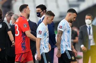 Desde la derecha, los jugadores argentinos Nicolás Otamendi, Giovani Lo Celso y Emiliano Martínez se retiran de la cancha tras la interrupción del partido contra Brasil por las eliminatorias del Mundial