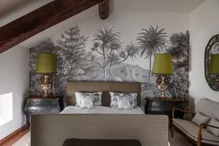 Dos veladores de anticuario se recortan sobre el mural ‘Jungle Land’ (Rebel Walls), que –en este dormitorio– se aplicó en versión blanco y negro.