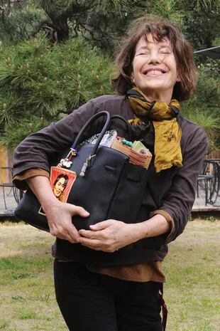 Abrazada a la icónica cartera que lleva su apellido, Birkin, sale de una conferencia de prensa en Tokio, Japón, en marzo de 2013.