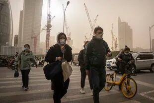 Personas con mascarillas caminan por una calle del distrito central de negocios de Pekín, el miércoles 22 de marzo de 2023.