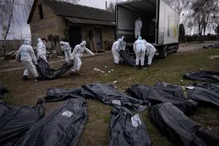 Volunteers load the bodies of civilians killed in Bucha onto a truck to be taken to a morgue for investigation, outside Kyiv, Ukraine, Tuesday, April 12, 2022. 