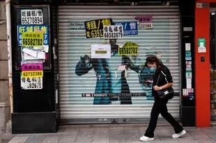 Un peatón camina frente a una tienda cerrada en Macao el 10 de octubre de 2022