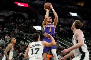El escolta de los Suns de Phoenix Devin Booker dispara en la segunda mitad del partido ante los Spurs de San Antonio, el lunes 17 de enero de 2022, en San Antonio. (AP Foto/Eric Gay)