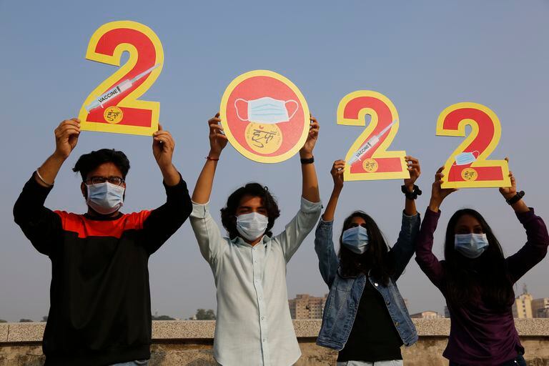 Los indios, que usan máscaras para ayudar a frenar la propagación del coronavirus, sostienen los recortes para dar la bienvenida a 2022 en la víspera de Año Nuevo en Ahmedabad, India