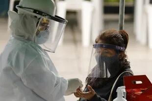 Un trabajador de la salud realiza una prueba rápida a una mujer durante el estado de emergencia sanitaria en la municipalidad de Villa María del Triunfo, en Lima