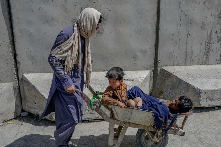 Un hombre lleva a niños en una carretilla mientras se apresuran a pasar a Pakistán desde la frontera con Afganistán en Spin Boldak el 25 de septiembre de 2021