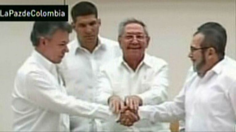El presidente de Colombia, Juan Manuel Santos, y el jefe máximo de la guerrilla de las FARC, Rodrigo Londoño Echeverri, alias Timochenko se dan la mano, con Raúl Castro de fondo