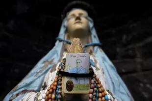 Una gruta religiosa con una estatua de la Virgen María sosteniendo una tarjeta de oración del Papa Francisco y varios juegos de rosarios se encuentra en el borde de la carretera cerca del condado de Mayo, pueblo de Claremorris
