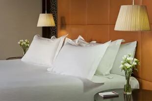 Almohadas bien mullidas y luces puntuales junto a la cama en una de las suites de NH Collection Lancaster