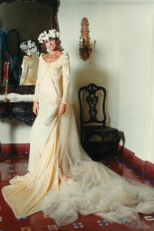 El diseño que Ginette Reynal usó en su boda con Julio Zavaleta, el 27 de abril de 1986, se convirtió en un traje icónico y uno de los más copiados. En esta ocasión, y con la complicidad de la novia, Gino se decantó por un diseño totalmente lánguido, dado que la estatura, los hombros y la fuerza de la cara de la modelo lo permitían, al que le dio su toque con la inmensa y larguísima cola de tul y el tocado de flores de seda que caían sobre la espalda.
