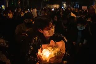 Un manifestante sostiene flores y velas en Pekín, el domingo 27 de noviembre de 2022.