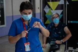 Un trabajador de la salud se prepara para administrar una dosis de la vacuna china CoronaVac a un docente en un centro de vacunación en Santiago de Chile, el 01 de marzo de 2021
