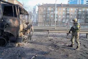 Un soldado ucraniano camina frente a un vehículo militar quemado, el sábado 26 de febrero de 2022, en Kiev, Ucrania.