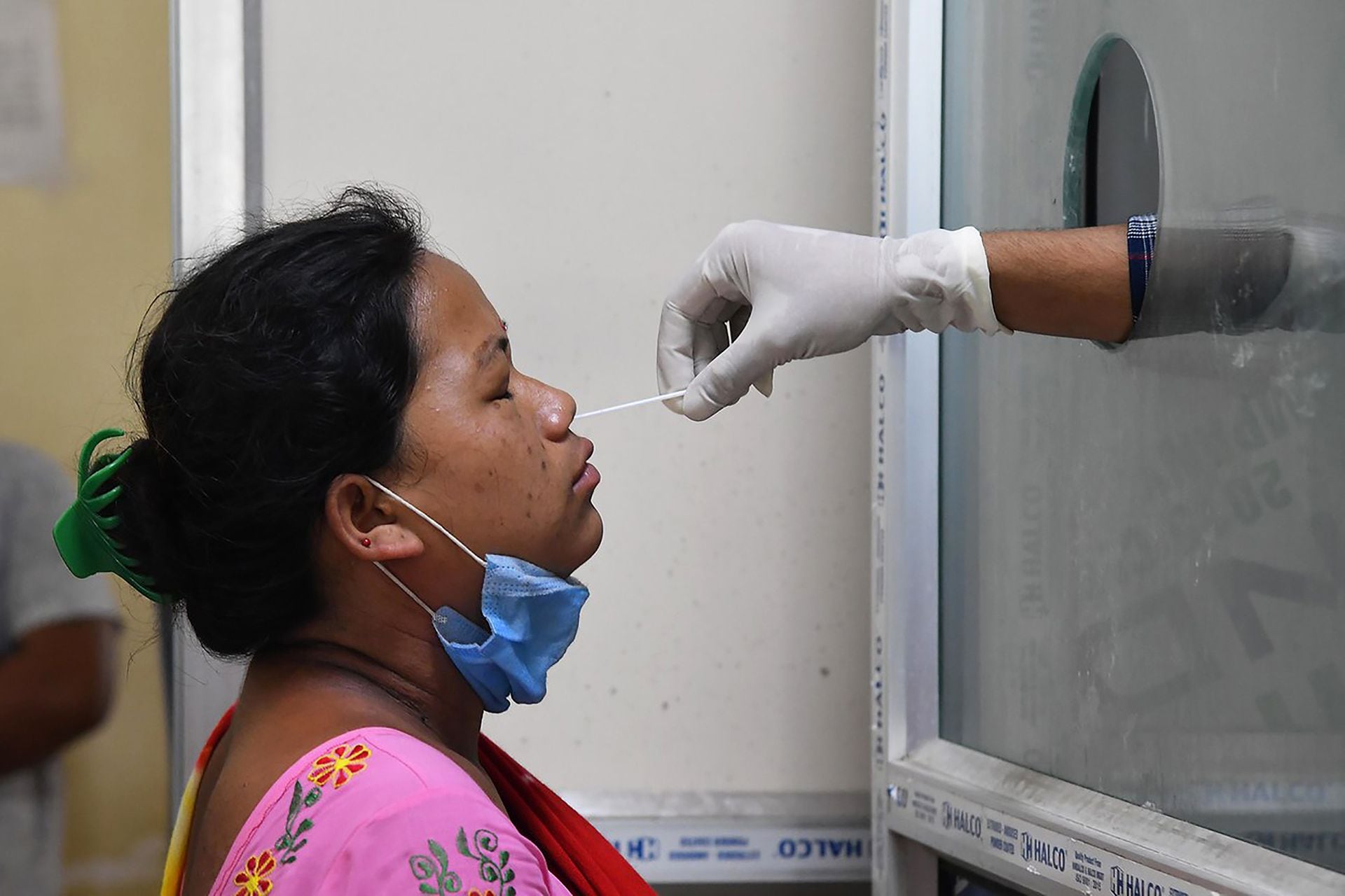 Un trabajador de salud le realiza un hisopado a una mujer en un centro de pruebas en el hospital MMC Covid en Guwahati, India