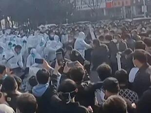 Esta imagen tomada de un vídeo de AFP y publicada el 23 de noviembre de 2022 muestra a los trabajadores de la fábrica de iPhone de Foxconn en Zhengzhou, en el centro de China, enfrentándose a la policía antidisturbios y a personas con trajes de protección. 