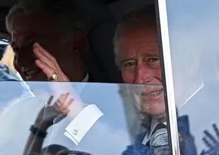 Britain's King Charles III waves to waiting members of the public as he arrives by car at Buckingham Palace on September 11, 2022 in London.  (Photo by Alain Jogaard/AFP)
