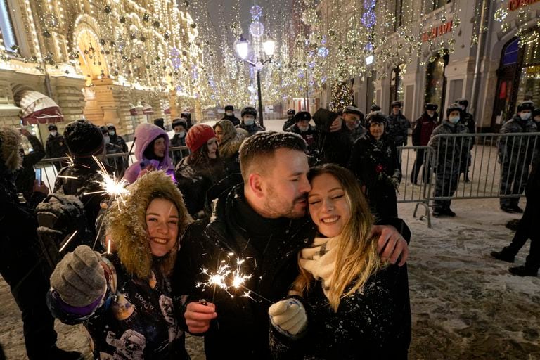 Varias personas celebran el Año Nuevo en la calle Nikolskaya cerca de la Plaza Roja, en Moscú, casi vacía debido a restricciones por la pandemia el sábado 1 de enero de 2022. (AP Foto/Alexander Zemlianichenko Jr)