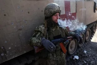 A Ukrainian soldier smokes next to an armored medical car in Donetsk