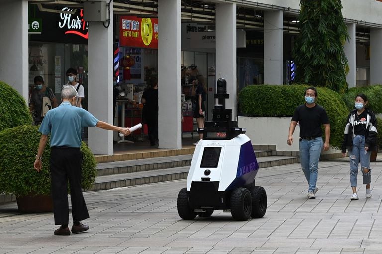 Un hombre gesticula frente al robot "Xavier" durante su patrullaje por un centro comercial de Singapur