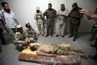 El cadáver de Khadafy es custodiado por unos combatientes rebeldes en unas instalaciones refrigeradas en Misrata, Libia, el viernes 21 de octubre de 2011