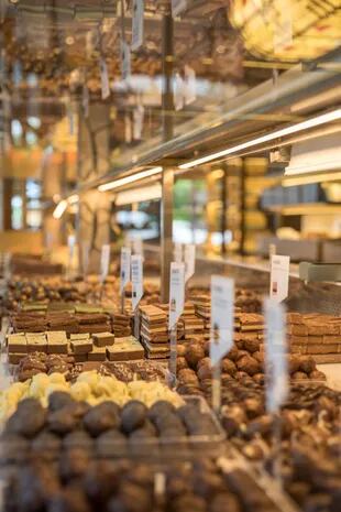 Las variedades de tabletas y trufas de chocolate de elaboración artesanal se exhiben en amplias vitrinas.