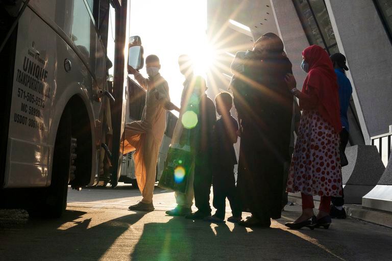 Las familias evacuadas de Kabul, Afganistán, esperan para abordar un autobús después de llegar al Aeropuerto Internacional Washington Dulles, en Chantilly, Virginia