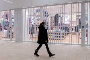 Una mujer camina frente a una tienda cerrada en un centro comercia, el domingo 2 de enero de 2022, en Montreal. (Graham Hughes /The Canadian Press via AP)