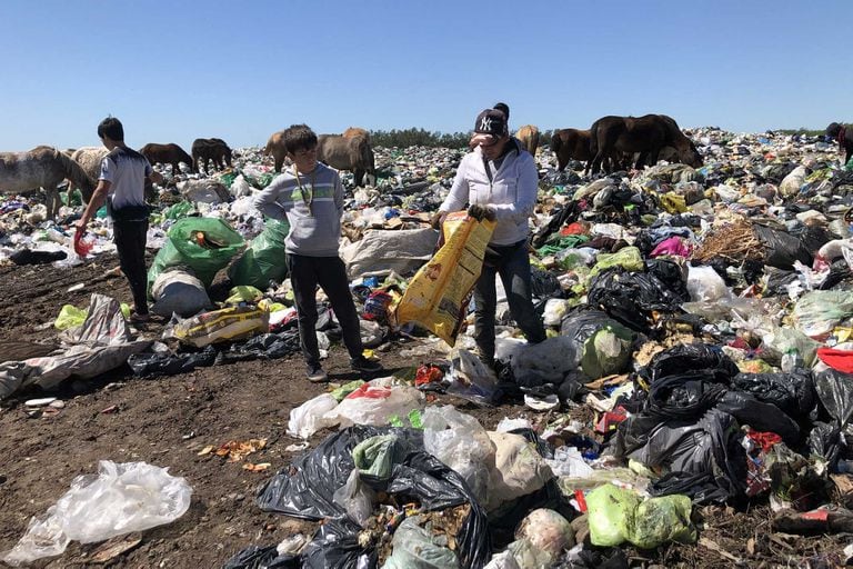 Violeta Cáceres y sus hijos Wenceslao y Josué separan la basura para después vender lo que se puede reciclar; atrás, los caballos se alimentan de lo que encuentran