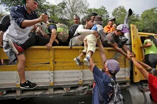 Los migrantes se suben a un camión que los trasladará en parte de su trayecto hacia EE.UU