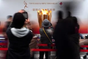 En esta foto de archivo del 24 de marzo de 2020, la gente toma fotos con la Llama Olímpica durante una ceremonia en la ciudad de Fukushima, Japón.